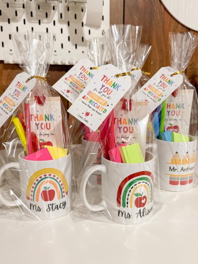 White mugs filled with stationery and thank you cards wrapped in cellophane bags.