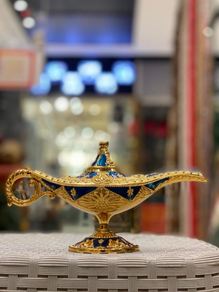 Ornate gold and blue genie lamp resting on a white woven table surface.