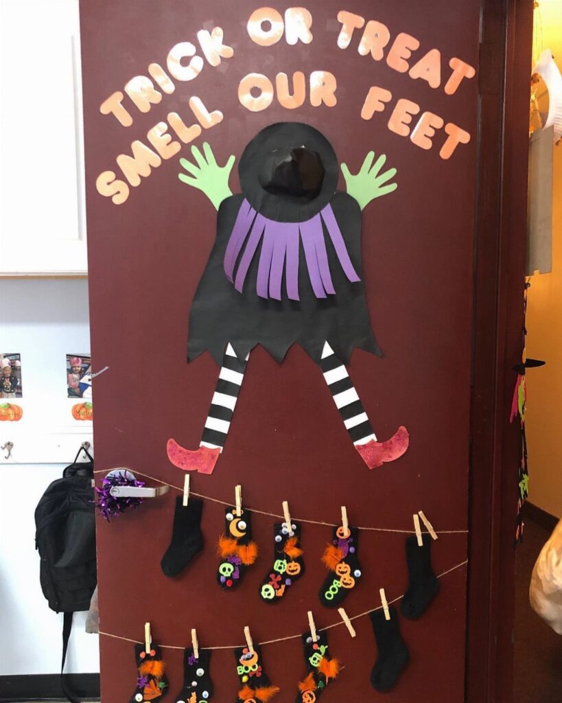 Halloween classroom door decoration featuring a paper witch and hanging decorated socks.