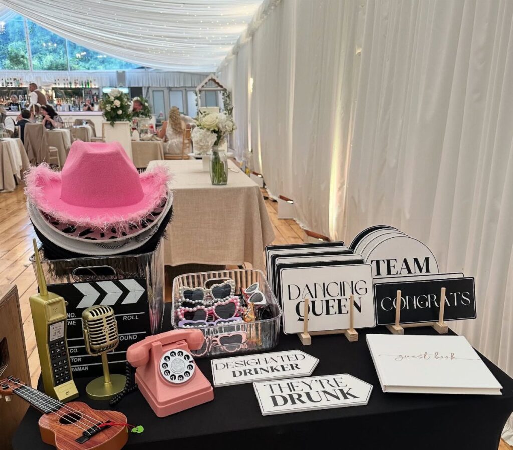 Party props including a pink cowboy hat and signs on a black table.