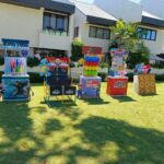 Colorful carnival game booths on a green lawn in front of a house.