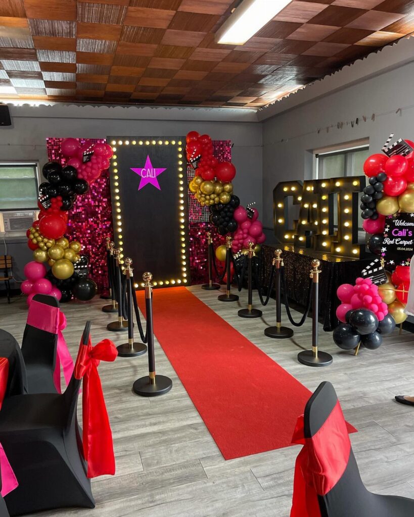 Red carpet runner leading to a star-themed photo backdrop with balloons and stanchions.