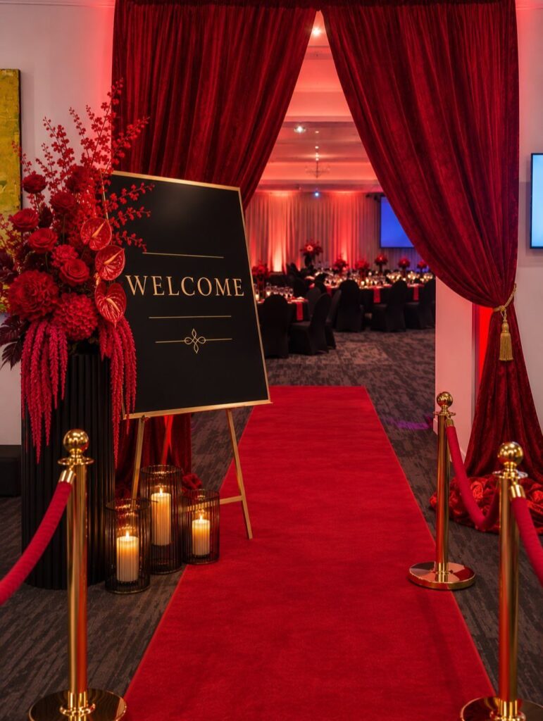 Red carpet entrance with gold stanchions, velvet ropes, and red curtains leading inside.