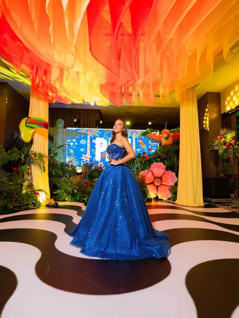 Woman in blue ballgown posing in a tropical Rio themed prom venue