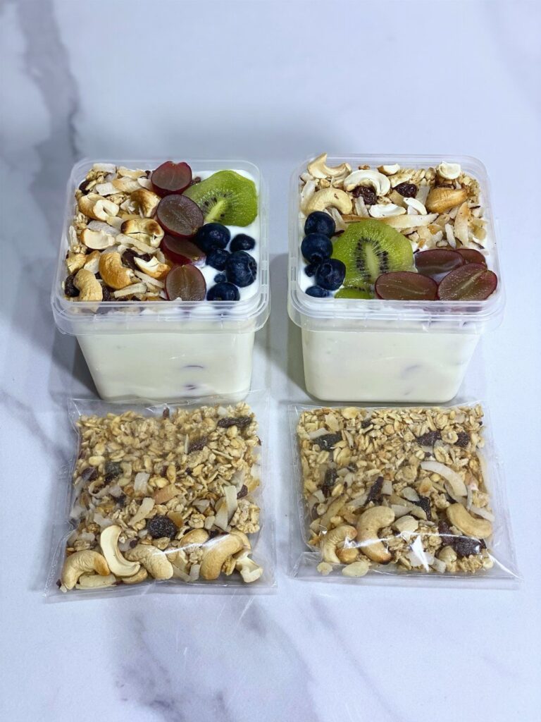 Yogurt parfaits in plastic containers with fruit and separate bags of granola.