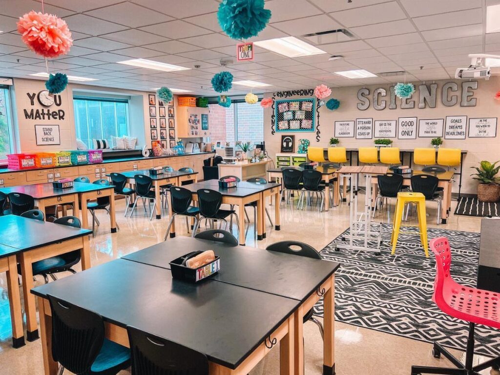 Science classroom with themed wall decorations, colorful ceiling pom-poms, and student workstations.