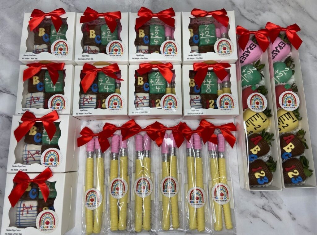 School-themed chocolate strawberries and treats in gift boxes with red ribbons.