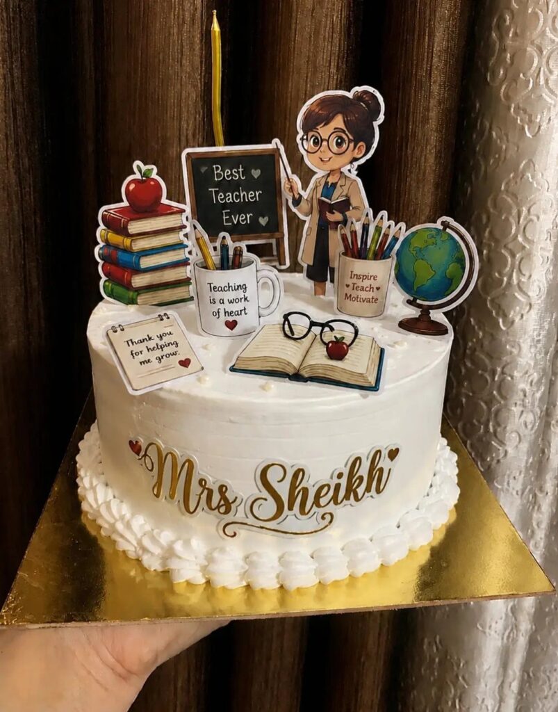 White frosted cake decorated with teacher-themed toppers and the name Mrs Sheikh.