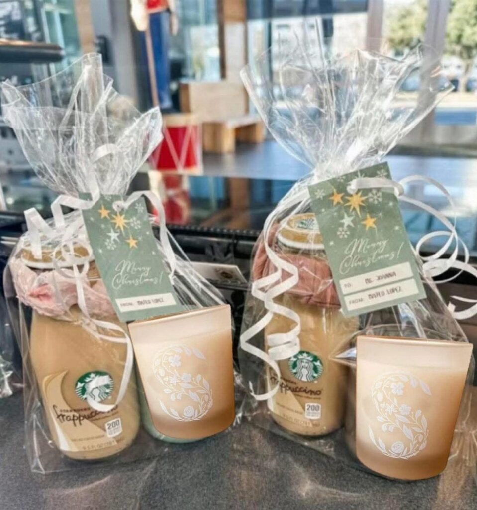 Two gift bags containing Starbucks bottled coffee and gold candles with Christmas tags.